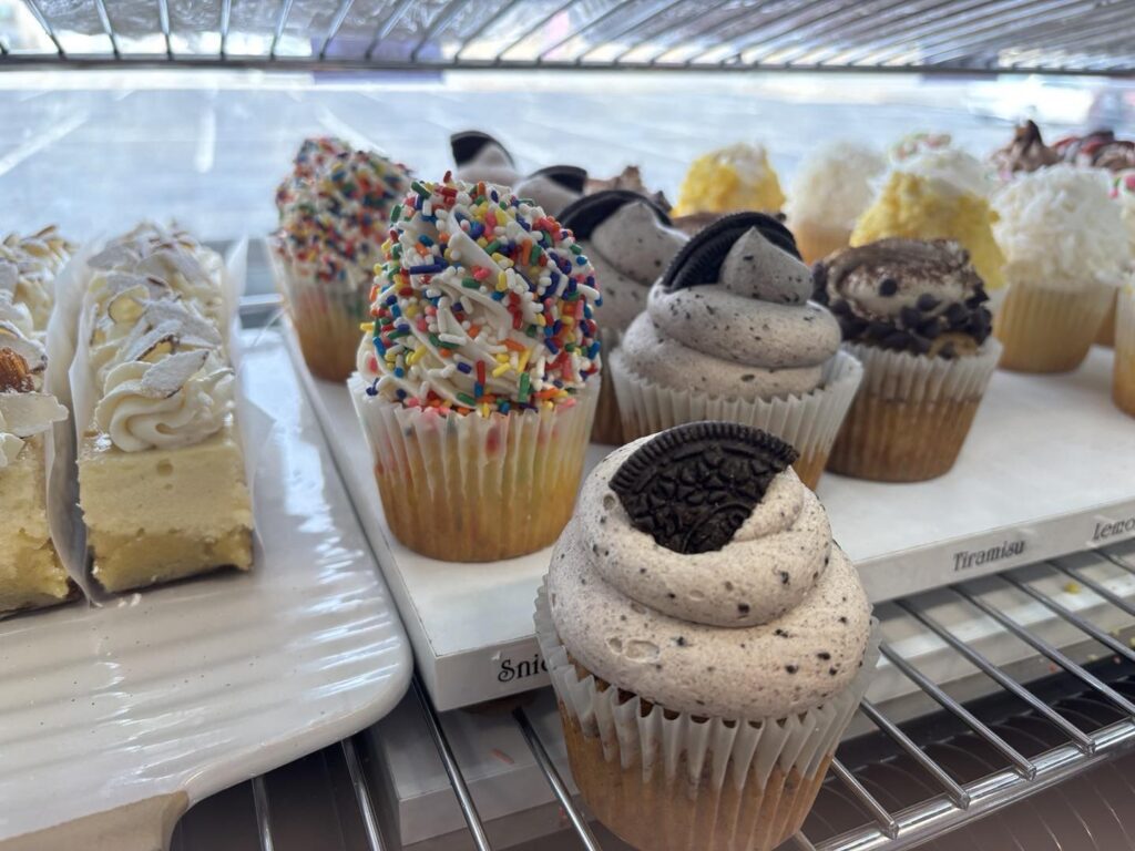 A high-quality flat lay of various cupcakes, cookies, brownies, and cake